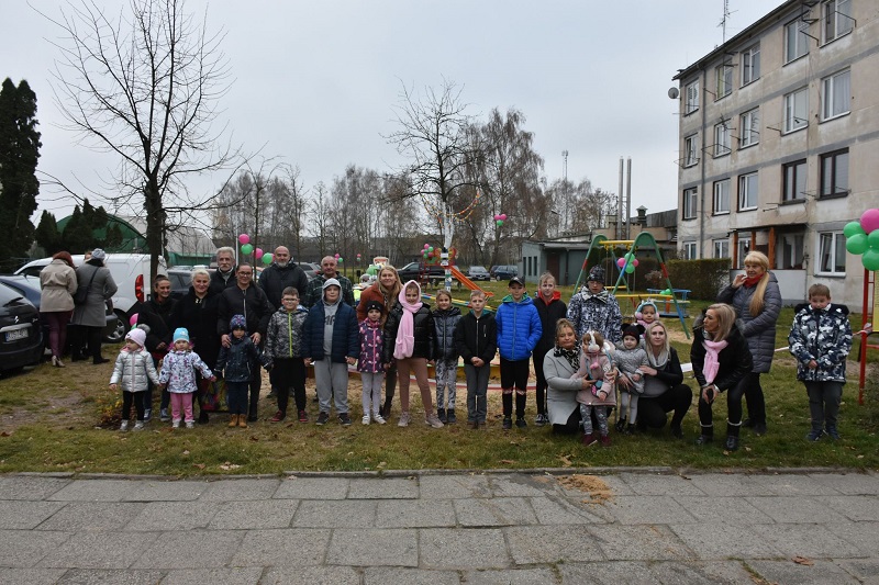 grupa ludzi zgromadzona na placu obok bloku